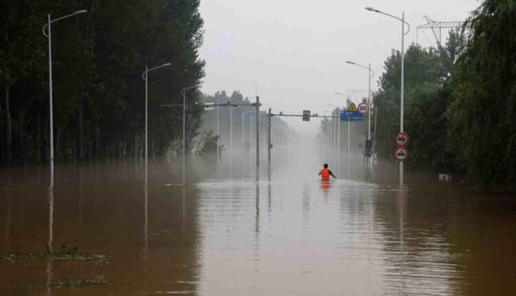 Un homme se frayant un chemin sur une route inondée après les pluies et les inondations provoquées par le typhon Doksuri, à Zhuozhou, dans la province du Hubei en Chine, le 3 août 2023. Ruters/Tingshu Wang