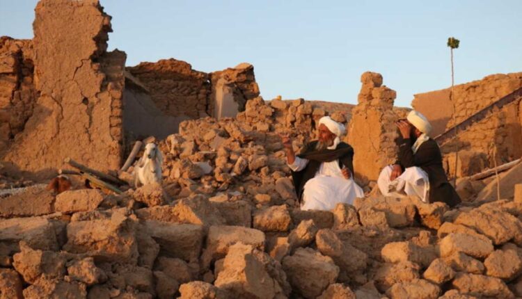 Des habitants afghans sont assis devant une maison endommagée par un tremblement de terre dans le village de Sarbuland à Zendeh Jan, dans la province de Herat, le 7 octobre 2023. © Mohsen Karimi, AFP (1)